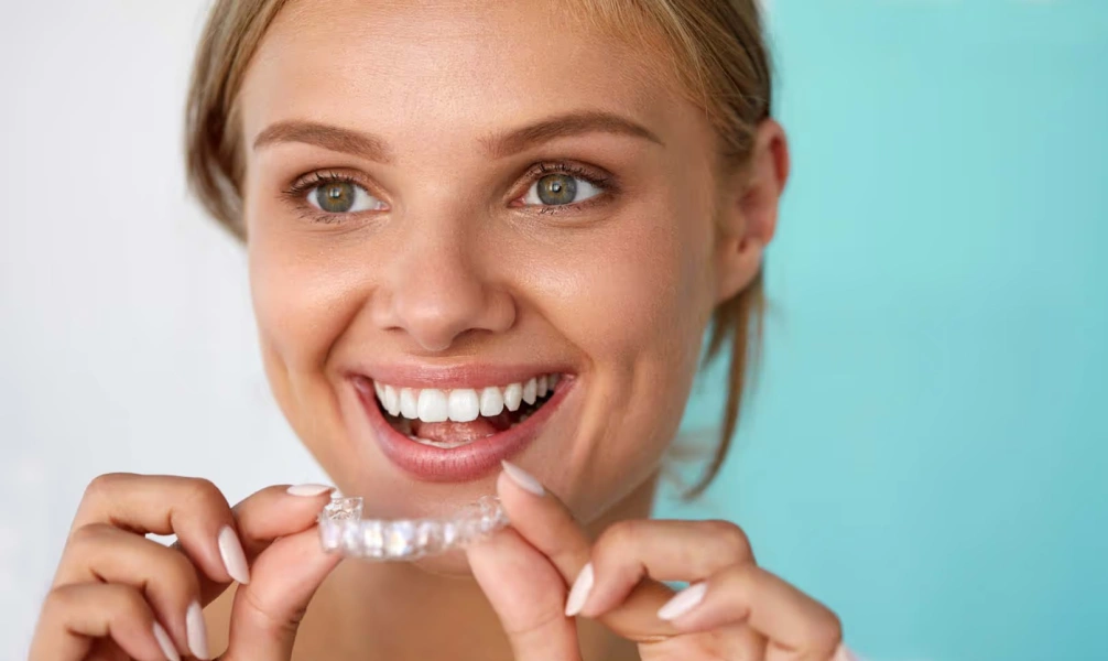 Woman holding Invisalign clear aligners and smiling