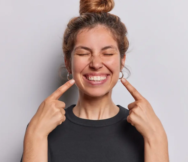 Woman pointing to her smile after cosmetic dental treatment