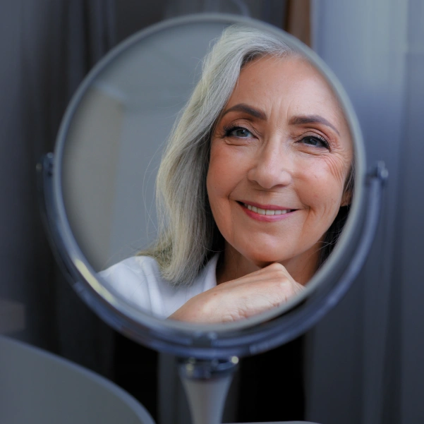 Woman checking her smile after dental bridge treatment