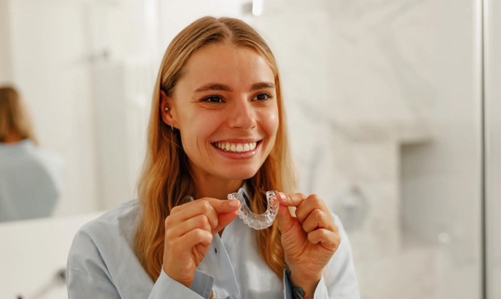 Woman holding a clear night guard used for bruxism treatment