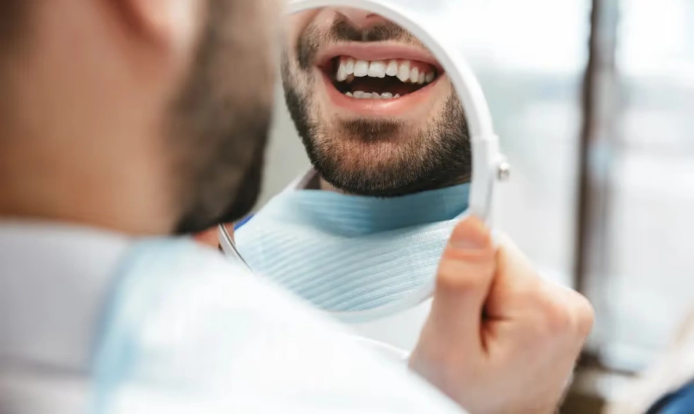 Man smiling while checking his teeth