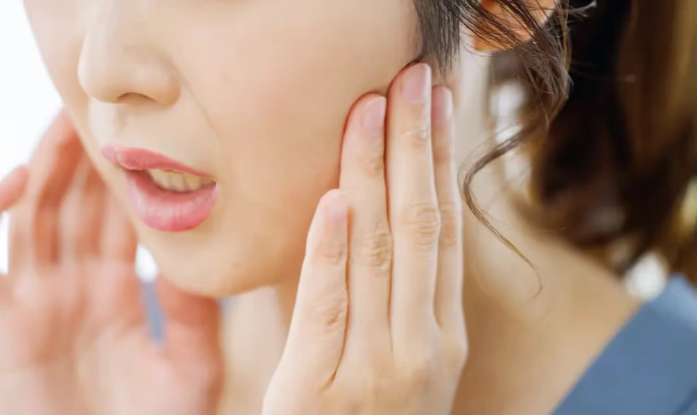 Woman touching her jaw due to TMJ discomfort