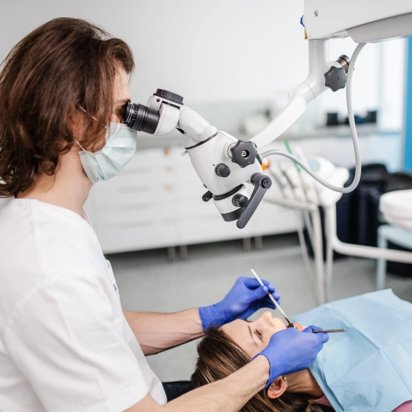 Dentist performing an endodontic procedure using a dental microscope