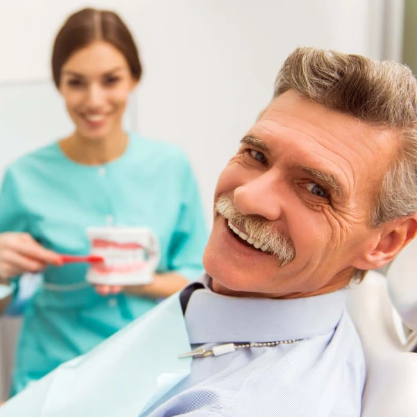 Patient holding a removable denture during a restorative dentistry visit
