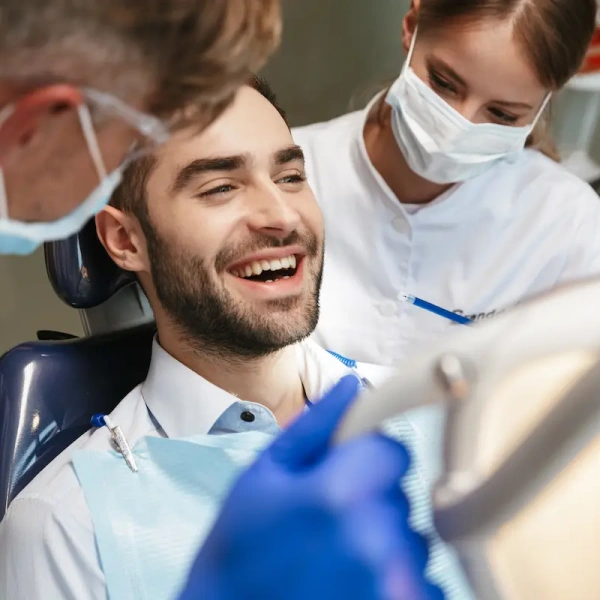 Patient smiling as dentist and hygienist examine him