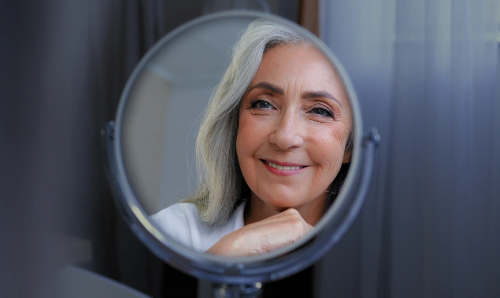 Woman checking her smile after dental bridge treatment