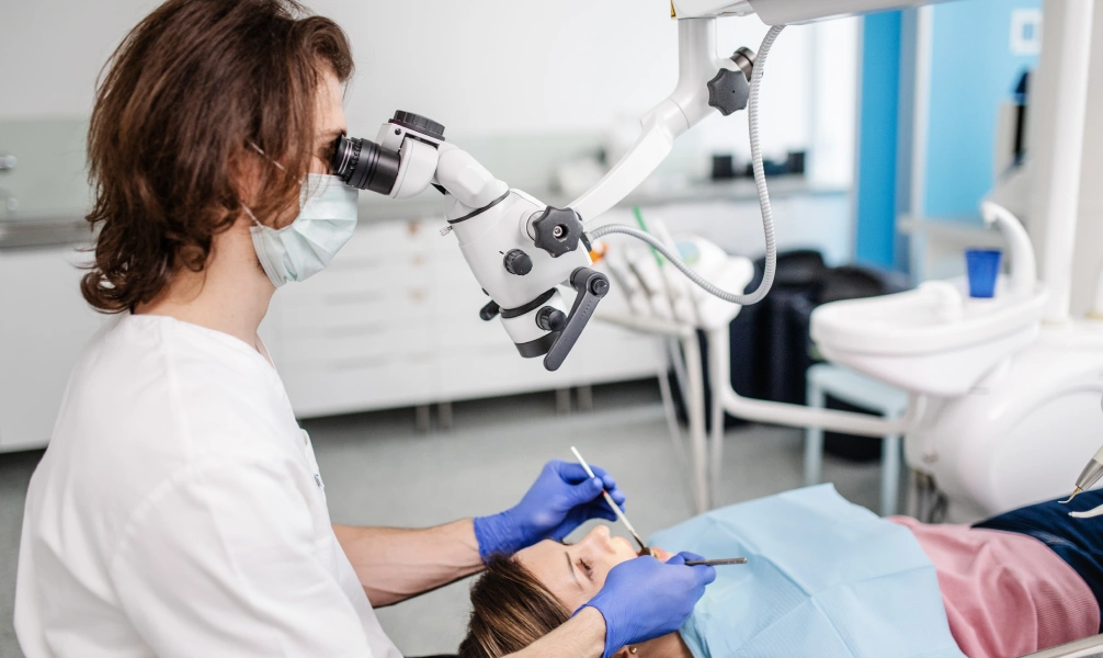 Dentist performing an endodontic procedure using a dental microscope