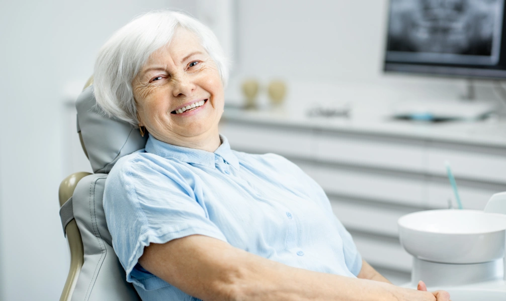 An older woman smiling during an implant-supported denture appointment