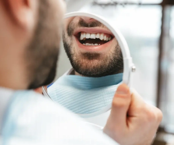 Patient checking a restored smile in a handheld mirror